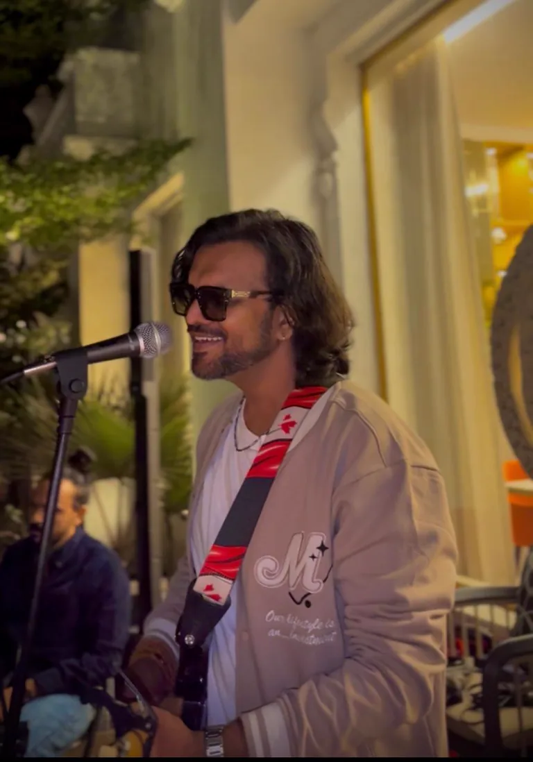 Aniket Patel singing at a microphone during a live performance